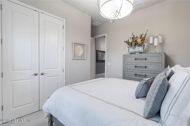 bedroom with a closet, wood finished floors, and a chandelier