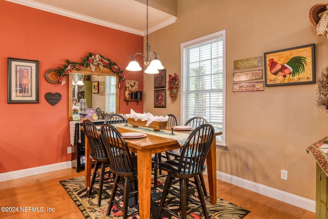 dining area featuring baseboards, a chandelier, crown molding, and wood finished floors