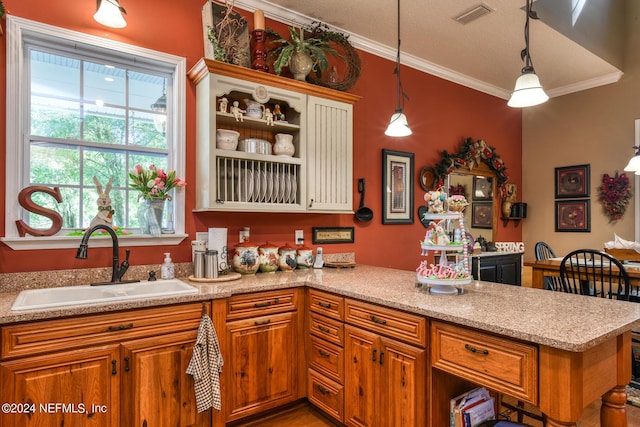 kitchen with ornamental molding, visible vents, a sink, a peninsula, and brown cabinets