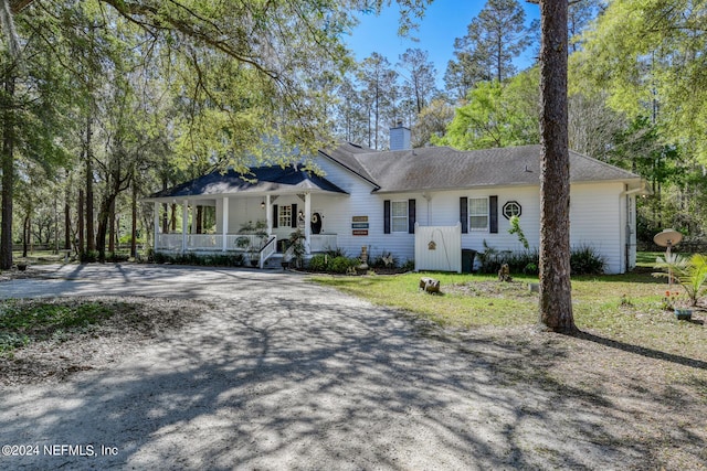 single story home featuring covered porch, a chimney, and driveway