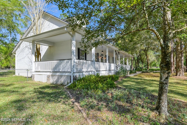 view of property exterior featuring a porch, fence, and a yard