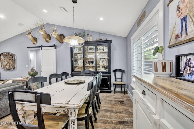 dining space with lofted ceiling, a barn door, wood finished floors, recessed lighting, and baseboards