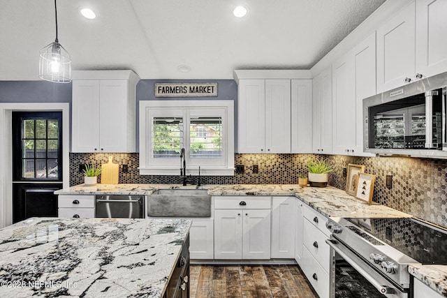 kitchen with stainless steel appliances, a sink, white cabinetry, backsplash, and dark wood-style floors