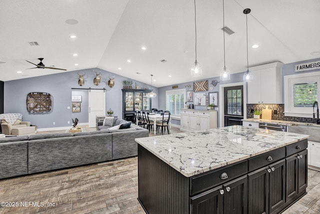kitchen featuring open floor plan, vaulted ceiling, light wood-style flooring, white cabinets, and dark cabinetry