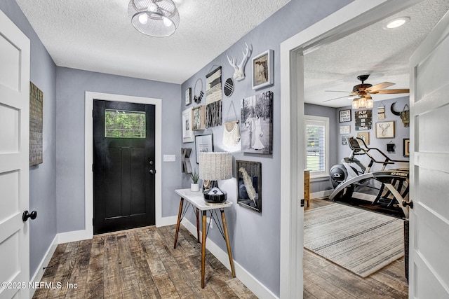 foyer featuring a textured ceiling, wood finished floors, baseboards, and ceiling fan