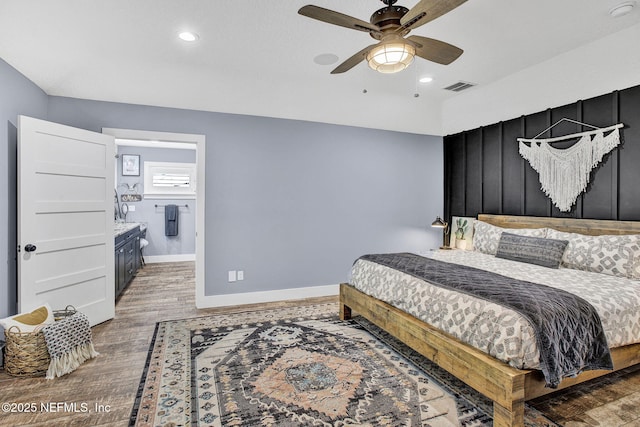 bedroom featuring wood finished floors, baseboards, recessed lighting, ceiling fan, and ensuite bath