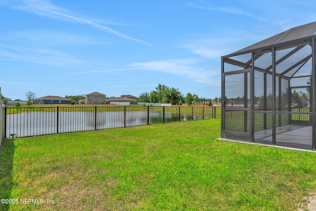 view of yard featuring fence, a water view, and a lanai