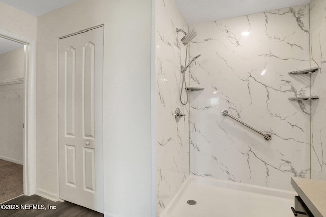 bathroom featuring a closet, a marble finish shower, wood finished floors, and vanity