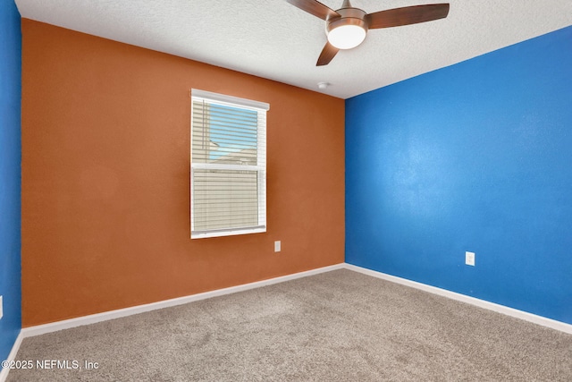 empty room with a textured ceiling, carpet, baseboards, and a ceiling fan