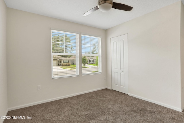 carpeted empty room featuring baseboards and ceiling fan