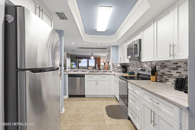 890 A1A Beach Blvd Unit 39, Saint Augustine, FL 32080 - kitchen with appliances with stainless steel finishes, a tray ceiling, tasteful backsplash, white cabinetry, and light tile patterned floors