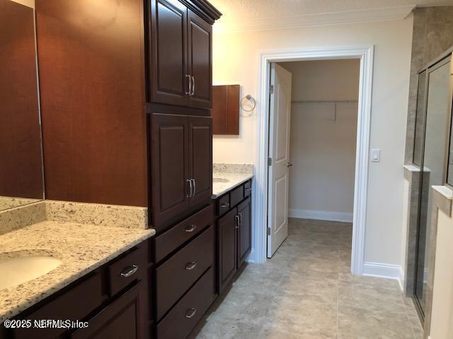 71 Utina Way, Saint Augustine, FL 32084 - bathroom with a walk in closet, vanity, a stall shower, and ornamental molding