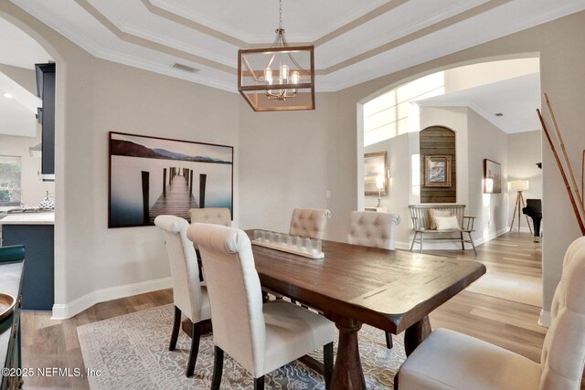 105 Calle Norte, Saint Augustine, FL 32095 - dining room with arched walkways, light wood-style floors, a raised ceiling, a chandelier, and ornamental molding