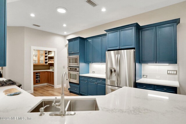 105 Calle Norte, Saint Augustine, FL 32095 - kitchen featuring appliances with stainless steel finishes, blue cabinetry, a sink, backsplash, and recessed lighting