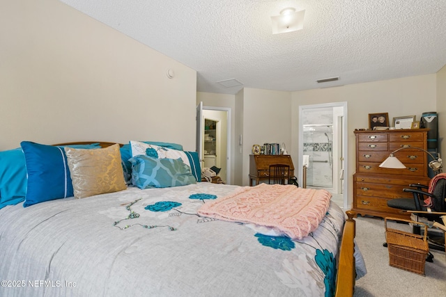 carpeted bedroom with a textured ceiling, ensuite bath, and visible vents