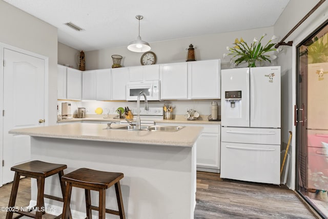 kitchen with white appliances, visible vents, a sink, light countertops, and white cabinets