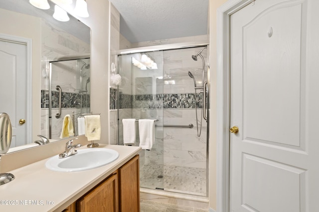 full bath featuring vanity, a shower stall, and a textured ceiling