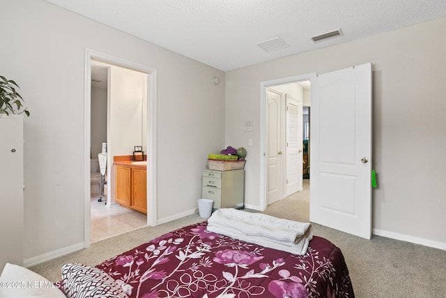 bedroom with baseboards, ensuite bath, visible vents, and light colored carpet