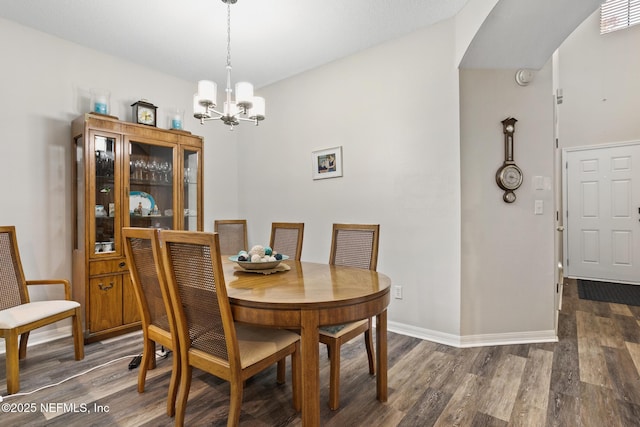 dining room with baseboards, an inviting chandelier, visible vents, wood finished floors, and arched walkways