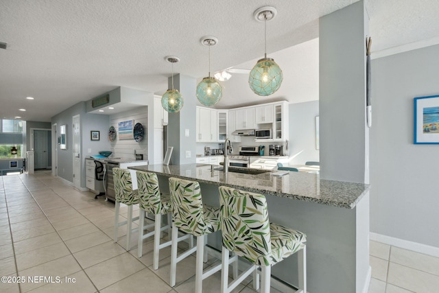 2122 S Fletcher Ave, Fernandina Beach, FL 32034 - kitchen with white cabinets, light tile patterned floors, a kitchen breakfast bar, and dark stone countertops