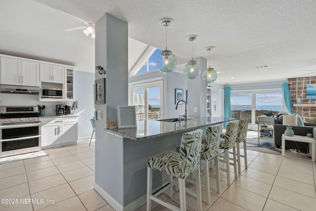 2122 S Fletcher Ave, Fernandina Beach, FL 32034 - kitchen with a sink, a breakfast bar area, light tile patterned floors, stone counters, and appliances with stainless steel finishes
