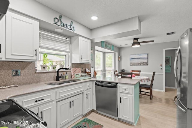 2632 Loopridge Dr, Orange Park, FL 32065 - kitchen with stainless steel appliances, a sink, a peninsula, white cabinetry, and tasteful backsplash
