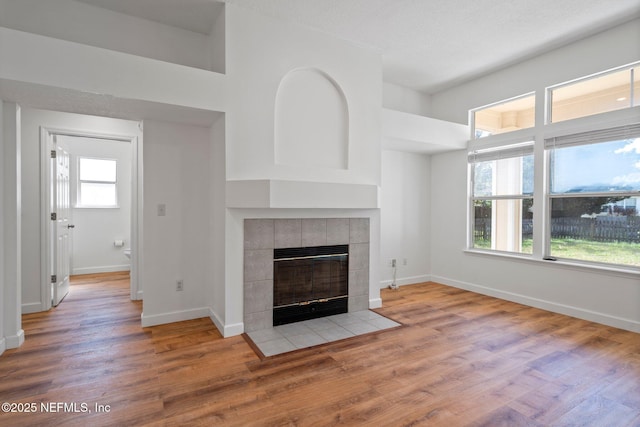unfurnished living room featuring a fireplace, baseboards, and wood finished floors