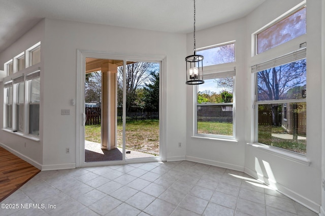 unfurnished dining area featuring a chandelier, baseboards, and light tile patterned flooring