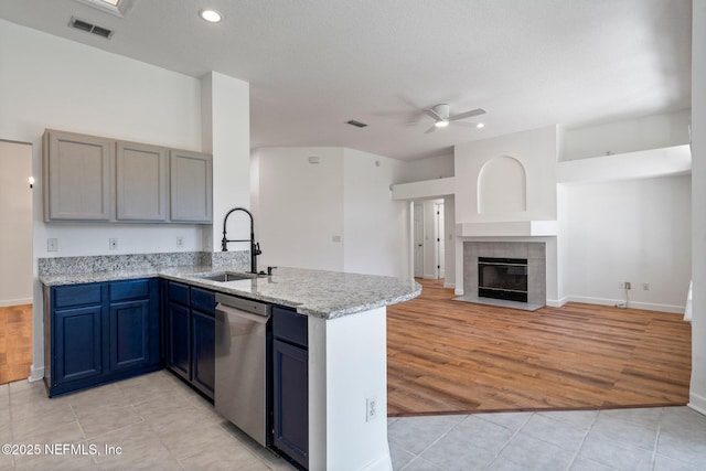 kitchen featuring a ceiling fan, stainless steel dishwasher, visible vents, a sink, and a peninsula