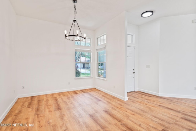 unfurnished dining area with a chandelier, baseboards, and light wood-type flooring