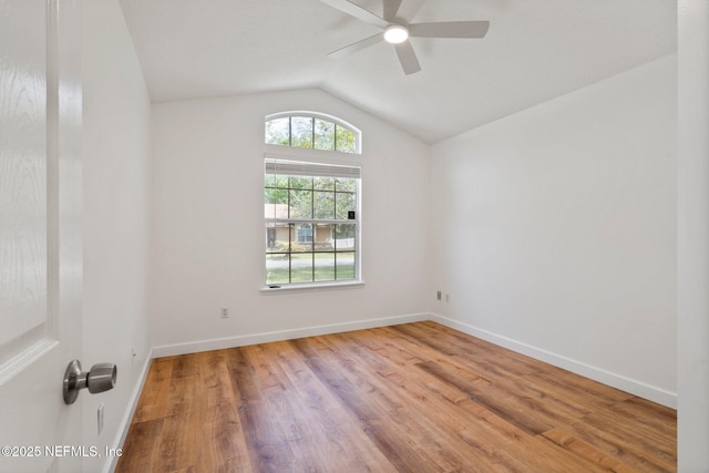 spare room featuring vaulted ceiling, baseboards, a ceiling fan, and wood finished floors