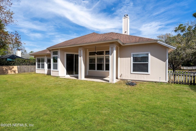 rear view of property with a yard, fence, a patio, and a shingled roof