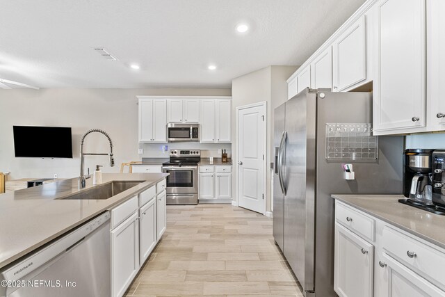 10350 Alder Creek Ln, Jacksonville, FL 32222 - kitchen with stainless steel appliances, a sink, light wood finished floors, white cabinetry, and recessed lighting