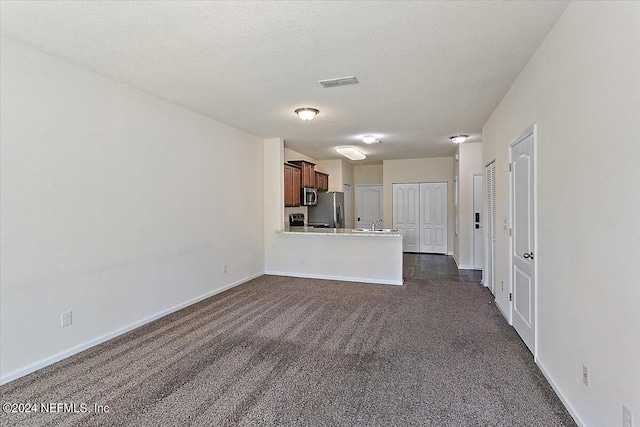 unfurnished living room featuring a textured ceiling, visible vents, baseboards, and dark colored carpet