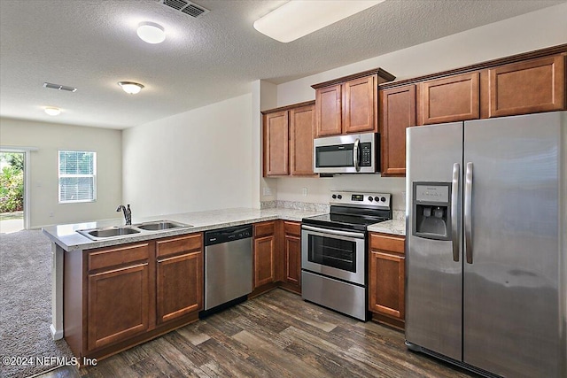 kitchen with a peninsula, a sink, stainless steel appliances, visible vents, and dark wood-style flooring