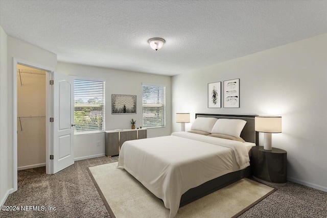 carpeted bedroom with a textured ceiling and baseboards