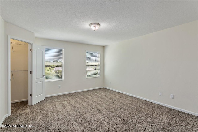 carpeted empty room featuring a textured ceiling and baseboards
