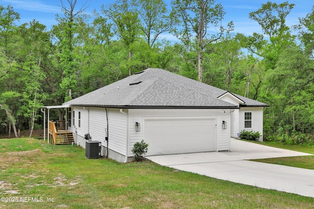 view of side of property with central air condition unit, roof with shingles, an attached garage, and a lawn