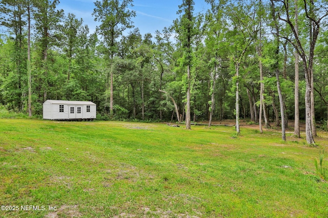 view of yard featuring an outbuilding and a view of trees