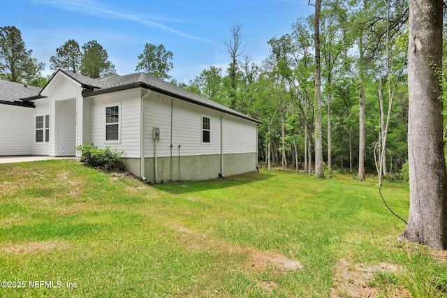 view of property exterior featuring a shingled roof and a yard