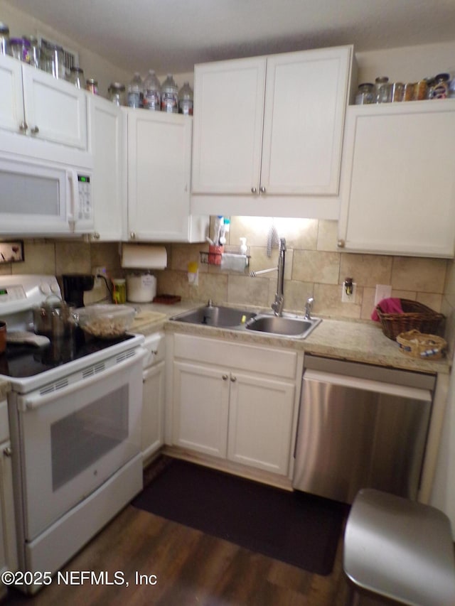 kitchen with a sink, white appliances, white cabinetry, and light countertops