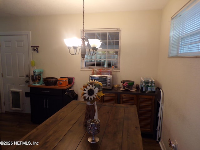 dining area with a notable chandelier, a toaster, and dark wood-type flooring