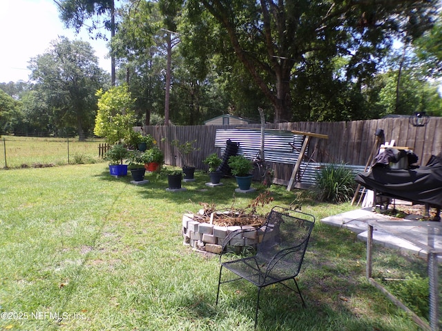 view of yard with a fenced backyard and a fire pit