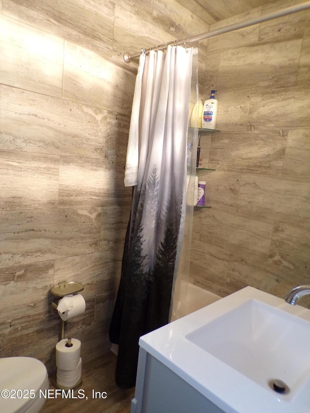 full bath with vanity, wood walls, toilet, and a tile shower