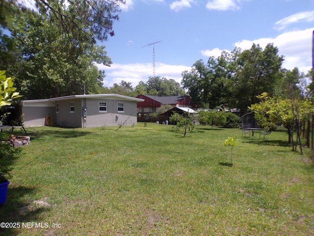 view of yard featuring a trampoline and an attached carport