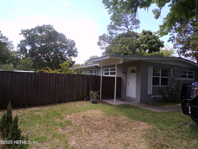 view of home's exterior with a lawn and fence