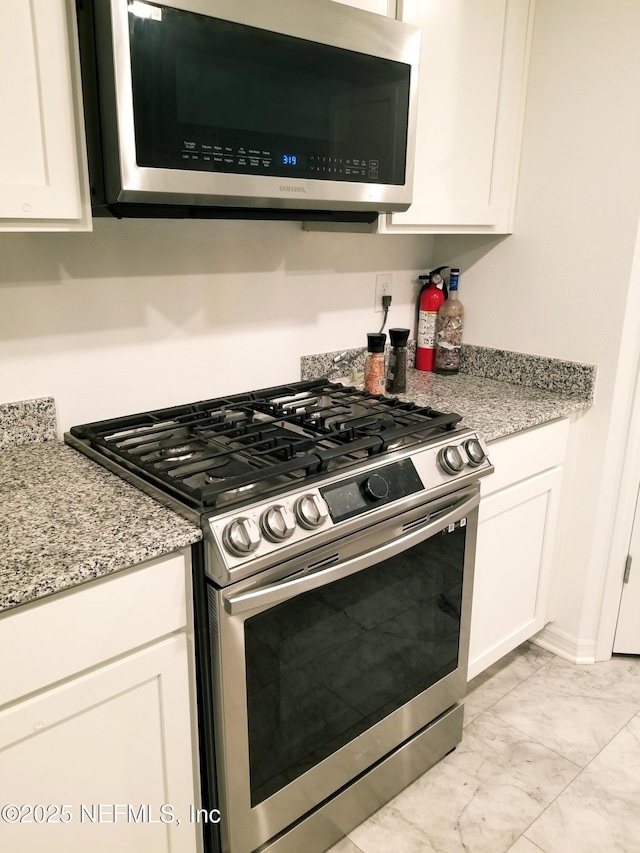 497 Live Oak Loop, Crescent City, FL 32112 - kitchen with white cabinetry, stainless steel appliances, marble finish floor, and light stone countertops