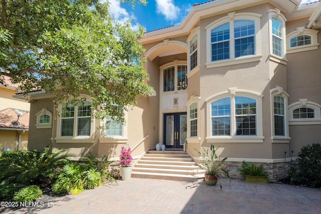 view of exterior entry with stucco siding and french doors