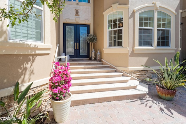 entrance to property featuring stucco siding and french doors