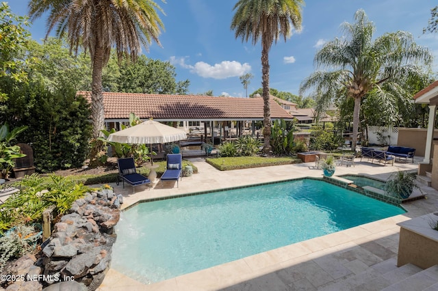 view of swimming pool featuring a pool with connected hot tub, fence, and a patio